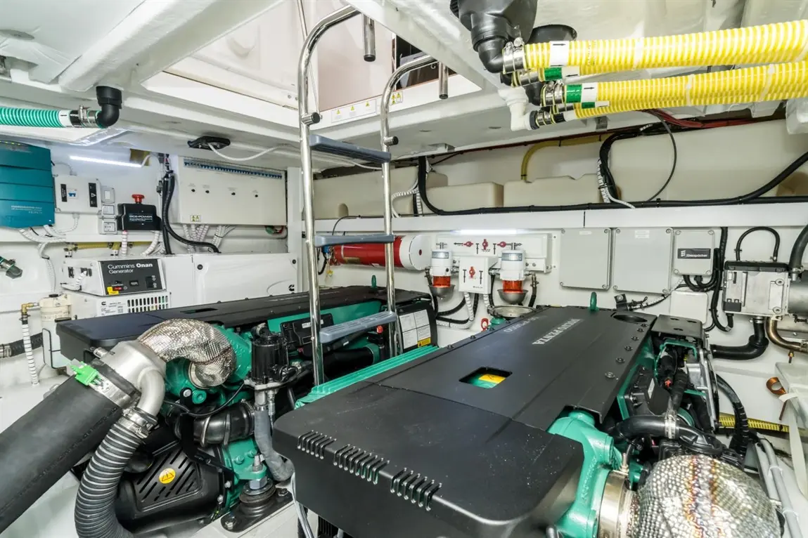 Engine room featuring two green marine engines, a Cummins Onan generator, pipes, and machinery for boat maintenance.